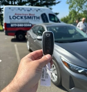 Freshly programmed Nissan Sentra Intelligent Key held in front of a gray Nissan Sentra with the American Best Locksmith service van behind